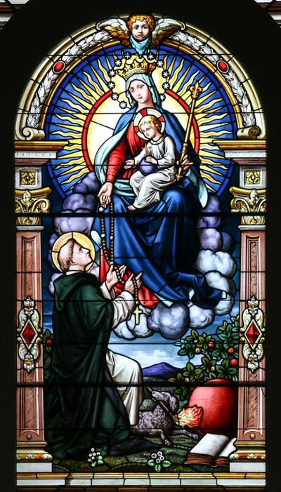 Photograph of a stained glass window featuring the Blessed Mother with St. Dominc