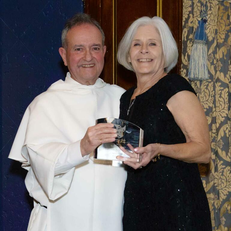 Fr. Jimmy Marchionda, O.P., presents Mary Lou Paluch Rafferty with the 2022 Veritas Award, honoring her leadership of the JS Paluch Co.