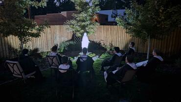 Dominicans praying to Rosary at night around a statue of Mary, the Mother of Mercy in the garden
